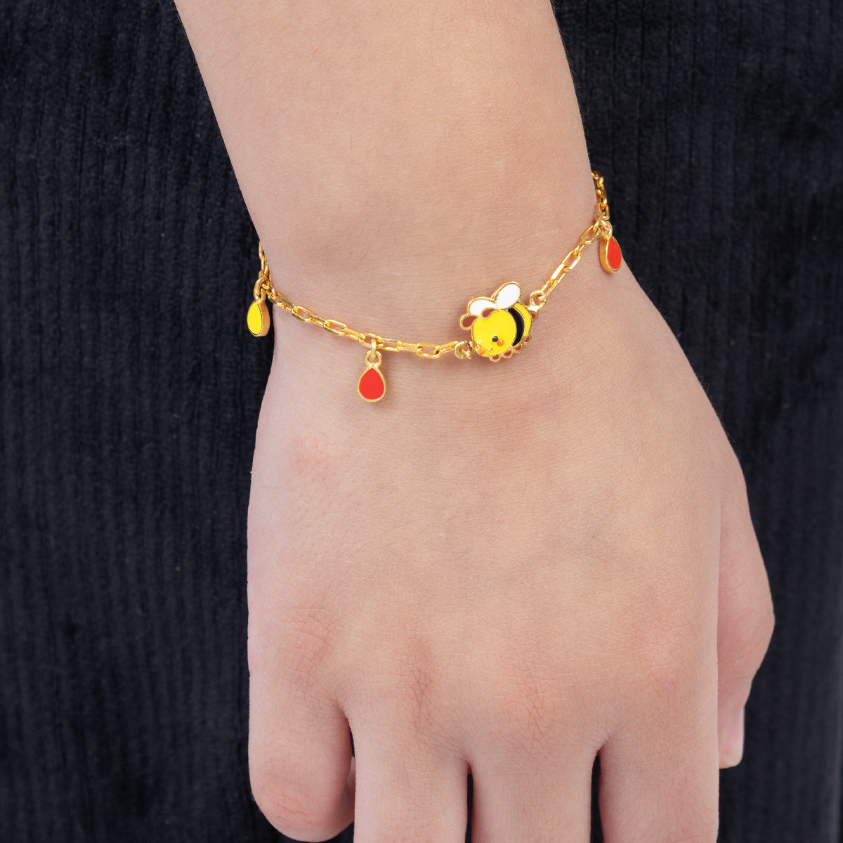 Tiny Jewels bracelet with bee charm on a wrist against a black background 
