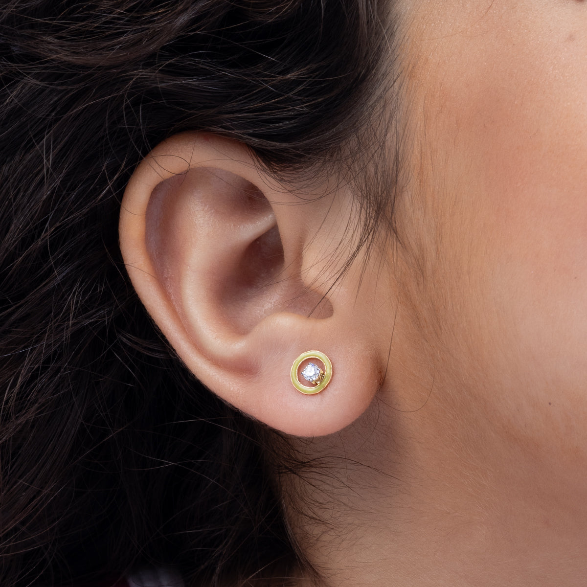 Tiny Jewels close-up of an ear wearing a gold earring with a clear gemstone.