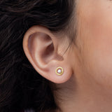 Tiny Jewels close-up of an ear wearing a gold earring with a clear gemstone.