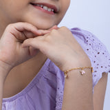 Tiny Jewels child wearing a gold bracelet with pink heart charm on a light purple background