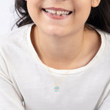 Tiny Jewels child wearing a gold necklace with a raindrop pendant on a plain background