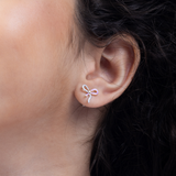 Tiny Jewels close-up of an ear wearing a bow-shaped earring with pink gemstones.