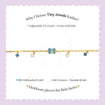 Tiny Jewels gold bracelet with blue accents on a wrist against a pink and black background