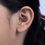 Tiny Jewels close-up of an ear wearing a pink and silver infinity symbol earring.