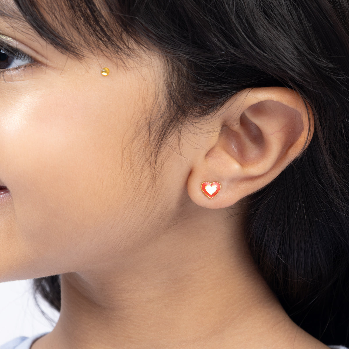 Tiny Jewels close-up of a person wearing a heart-shaped earring.