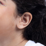 Tiny Jewels close-up of an ear with a floral stud earring on a neutral background