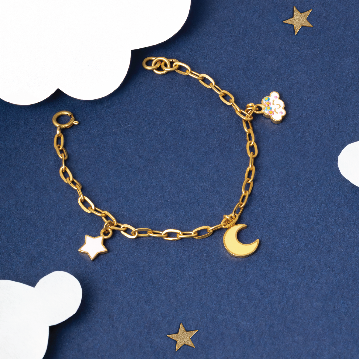 Tiny Jewels gold bracelet with star and moon charms on a blue background with stars and clouds.