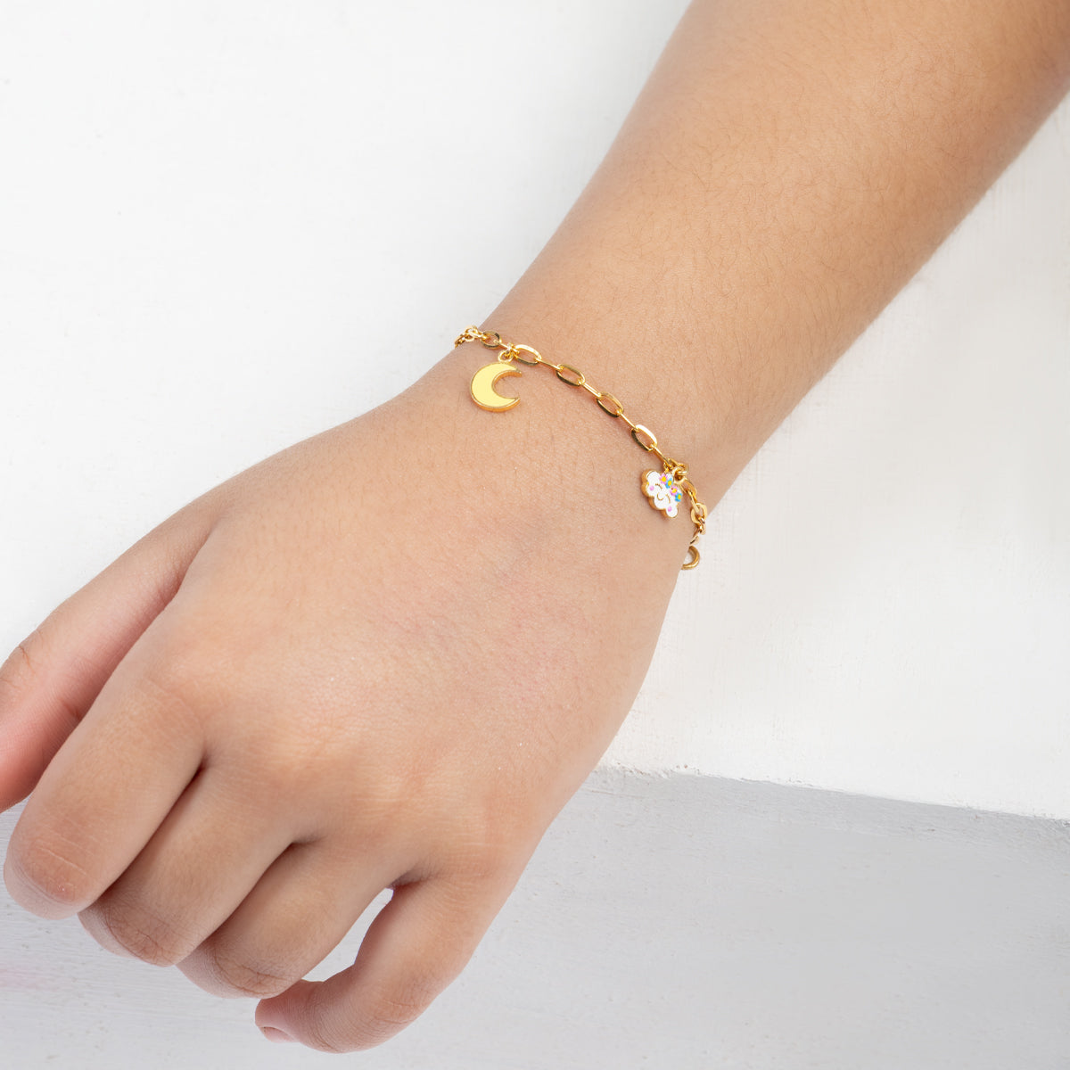 Tiny Jewels gold bracelet with a moon charm on a child's wrist against a white background