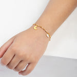 Tiny Jewels gold bracelet with a moon charm on a child's wrist against a white background