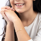 Tiny Jewels close-up of a child wearing a pearl bracelet on a white background