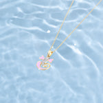 Gold necklace with a pink pendant on a water background  Tiny Jewels.