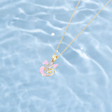 Gold necklace with a pink pendant on a water background  Tiny Jewels.