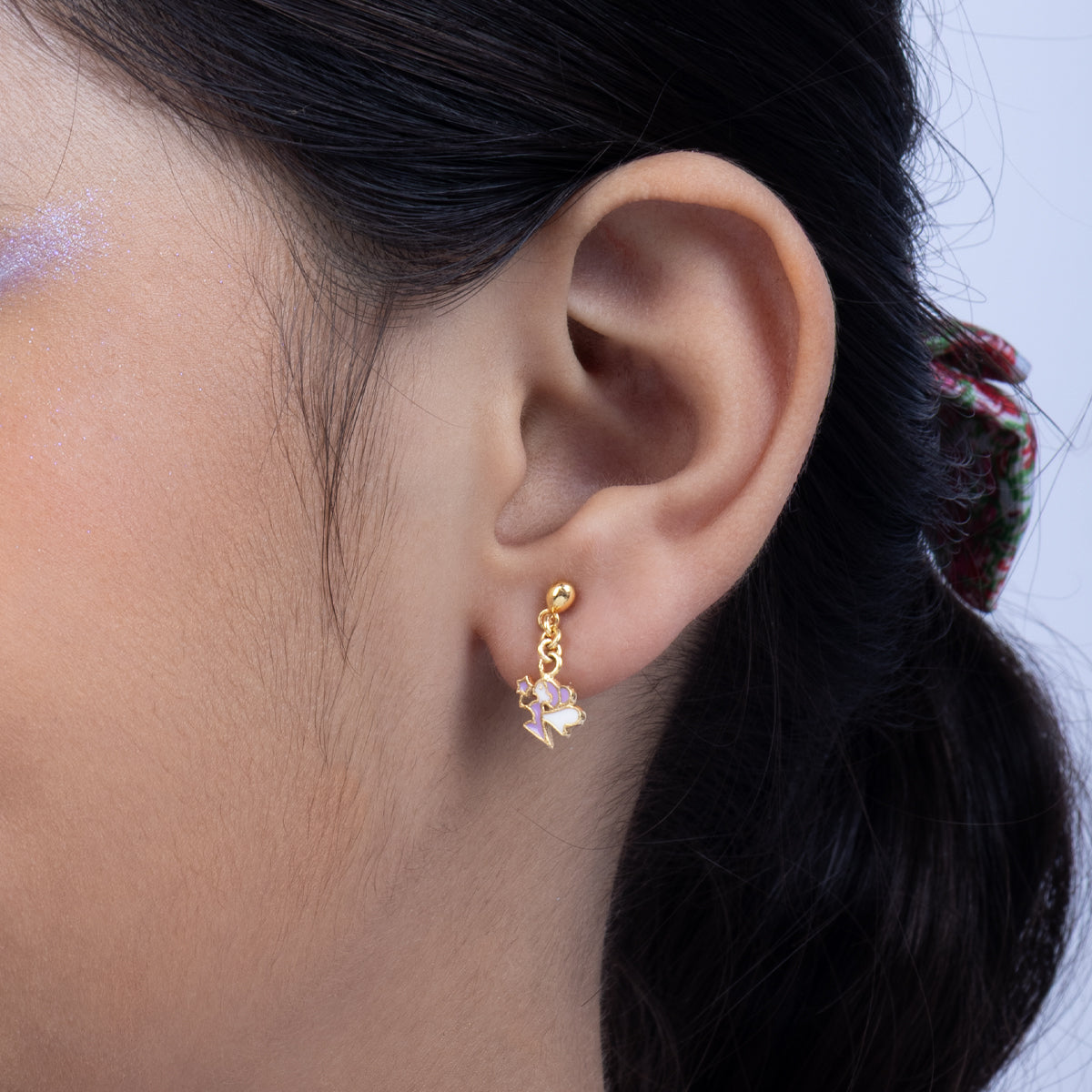 Tiny Jewels close-up of an ear wearing a gold earring with a pink gemstone.