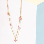 Tiny Jewels necklace with pink flower pendants on a light background