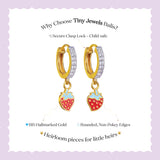 Tiny Jewels gold hoop earrings with strawberry charms on a white background with text about Tiny Jewels Balis.