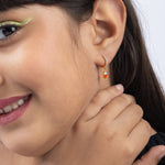 Tiny Jewels close-up of a woman wearing a hoop earring with a small heart charm.
