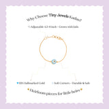 Tiny Jewels advertisement for Tiny Jewels Kadas bracelet with gold chain and blue evil eye charm on a light purple background.