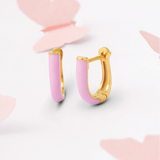 Tiny Jewels pink hoop earrings with gold accents on a light pink background