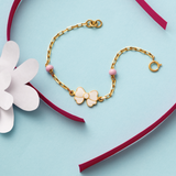 Tiny Jewels gold bracelet with a bow charm on a heart-shaped box with a white flower