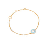 Tiny Jewels gold bracelet with a blue enameled circle and clear gemstone on a white background