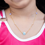 Tiny Jewels gold necklace with colorful beads worn by a person in a pink shirt