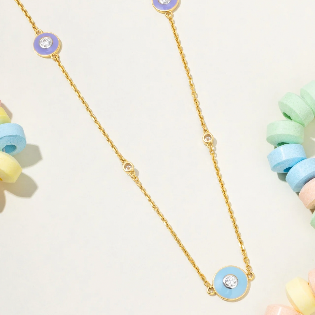 Tiny Jewels gold necklace with blue and green circular pendants on a white background