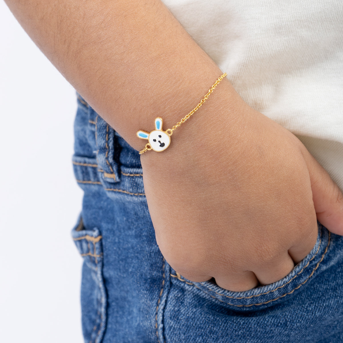 Tiny Jewels child's hand wearing a gold bracelet with a cartoon character charm on a white background