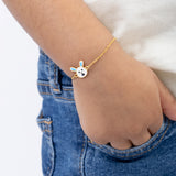 Tiny Jewels child's hand wearing a gold bracelet with a cartoon character charm on a white background