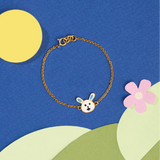Tiny Jewels gold bracelet with a bunny charm on a colorful background