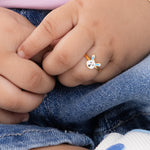 Tiny Jewels child's hand wearing a small bunny-shaped ring with denim pants in the background