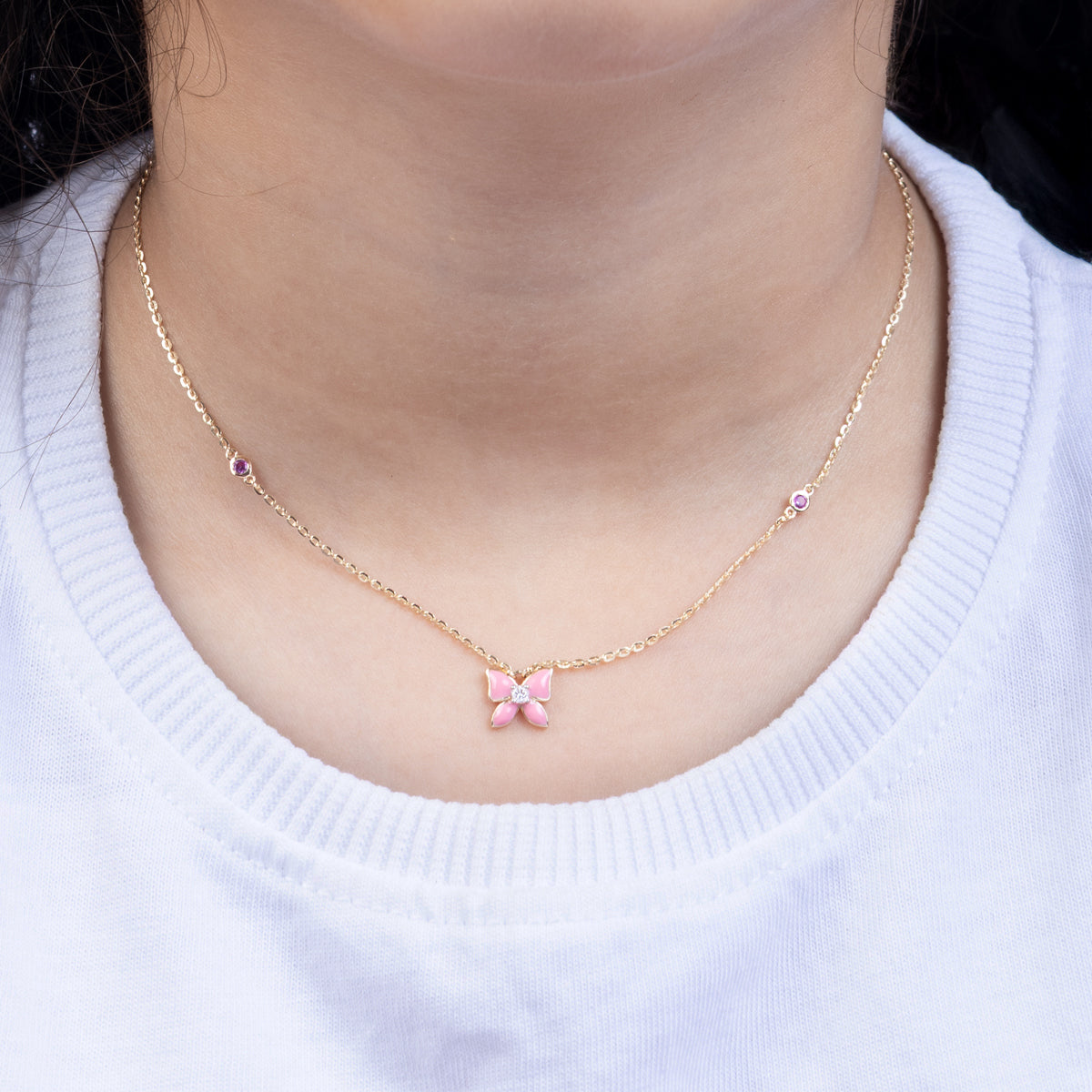 Tiny Jewels necklace with a pink butterfly pendant worn by a person on a white background