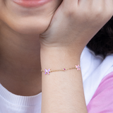 Tiny Jewels close-up of a person wearing a delicate bracelet with pink flowers on a light background