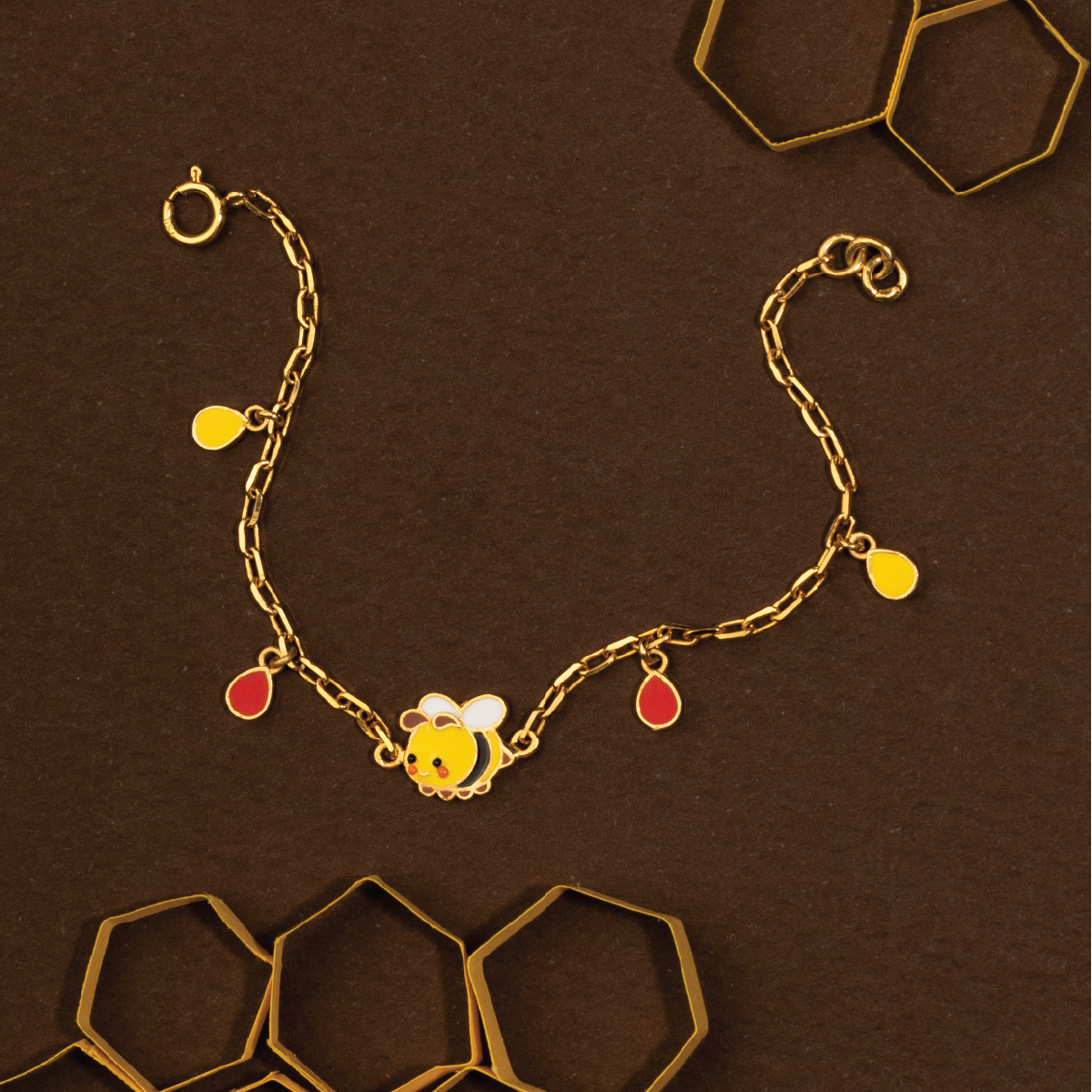 Tiny Jewels gold bracelet with a bee charm on a brown background