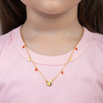 Tiny Jewels gold necklace with a bee pendant worn by a person in a pink shirt