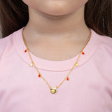 Tiny Jewels gold necklace with a bee pendant worn by a person in a pink shirt