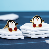 Tiny Jewels penguin-shaped earrings on a stack of white cards with a blue background