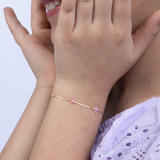 Tiny Jewels close-up of a person wearing a delicate bracelet with small pink flowers on a light background