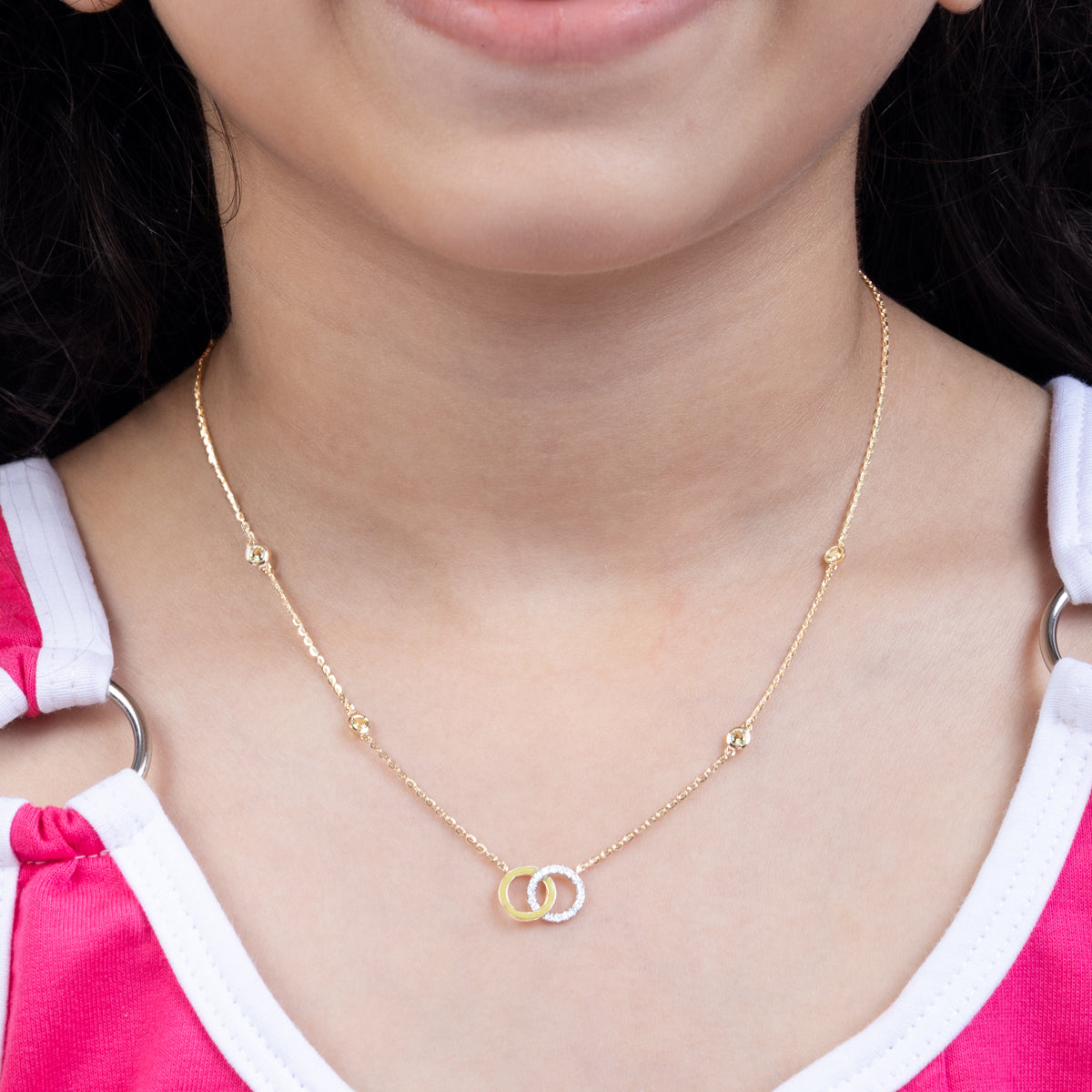 Tiny Jewels gold necklace with interlocking rings worn by a person