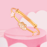Tiny Jewels gold bracelet with star and cloud designs on a pink cloud background