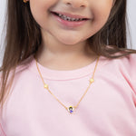 Tiny Jewels child wearing a gold necklace with a small pendant on a plain background