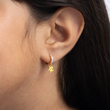 Tiny Jewels close-up of an ear wearing a gold hoop earring with a star charm.