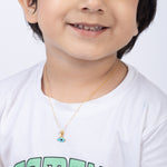 Tiny Jewels Child wearing a gold necklace with a blue pendant on a white background