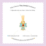Tiny Jewels gold pendant with blue bow design on a white card with text about Tiny Jewels Pendants.