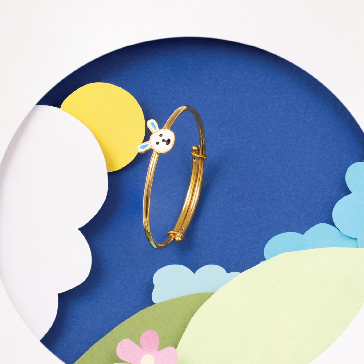 Tiny Jewels gold bracelet with a cartoon character on a colorful landscape background