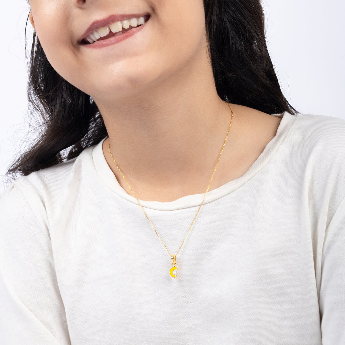 Tiny Jewels Person wearing a gold necklace with a yellow pendant on a white background