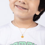 Tiny Jewels child wearing a gold necklace with a small pendant on a white background