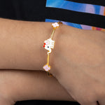 Tiny Jewels gold bracelet with a cartoon character on a wrist against a colorful background