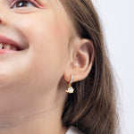 Tiny Jewels close-up of a child wearing a gold and diamond earring on a white background