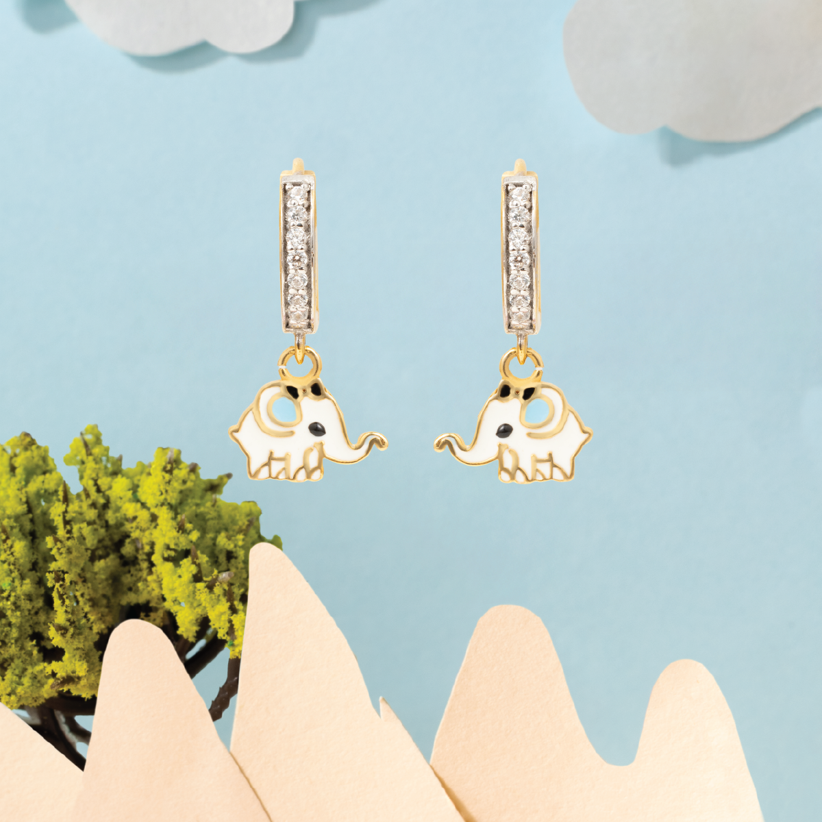 Tiny Jewels gold elephant earrings with diamond accents on a light blue background