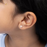 Tiny Jewels close-up of an ear wearing a small earring with a scallop shell design.